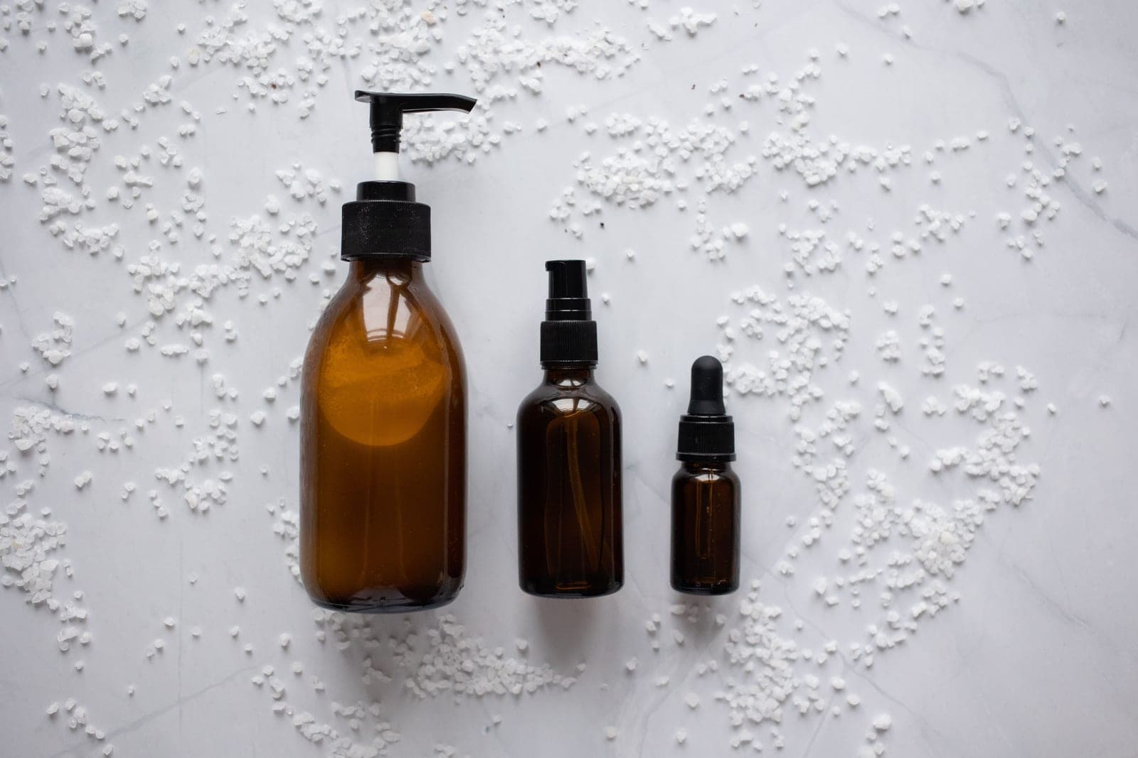 Skincare bottles seen from above on a white marble table