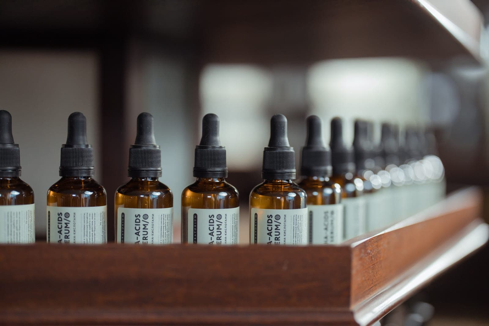 A row of serum bottles with dropper caps lined up on a wooden shelf