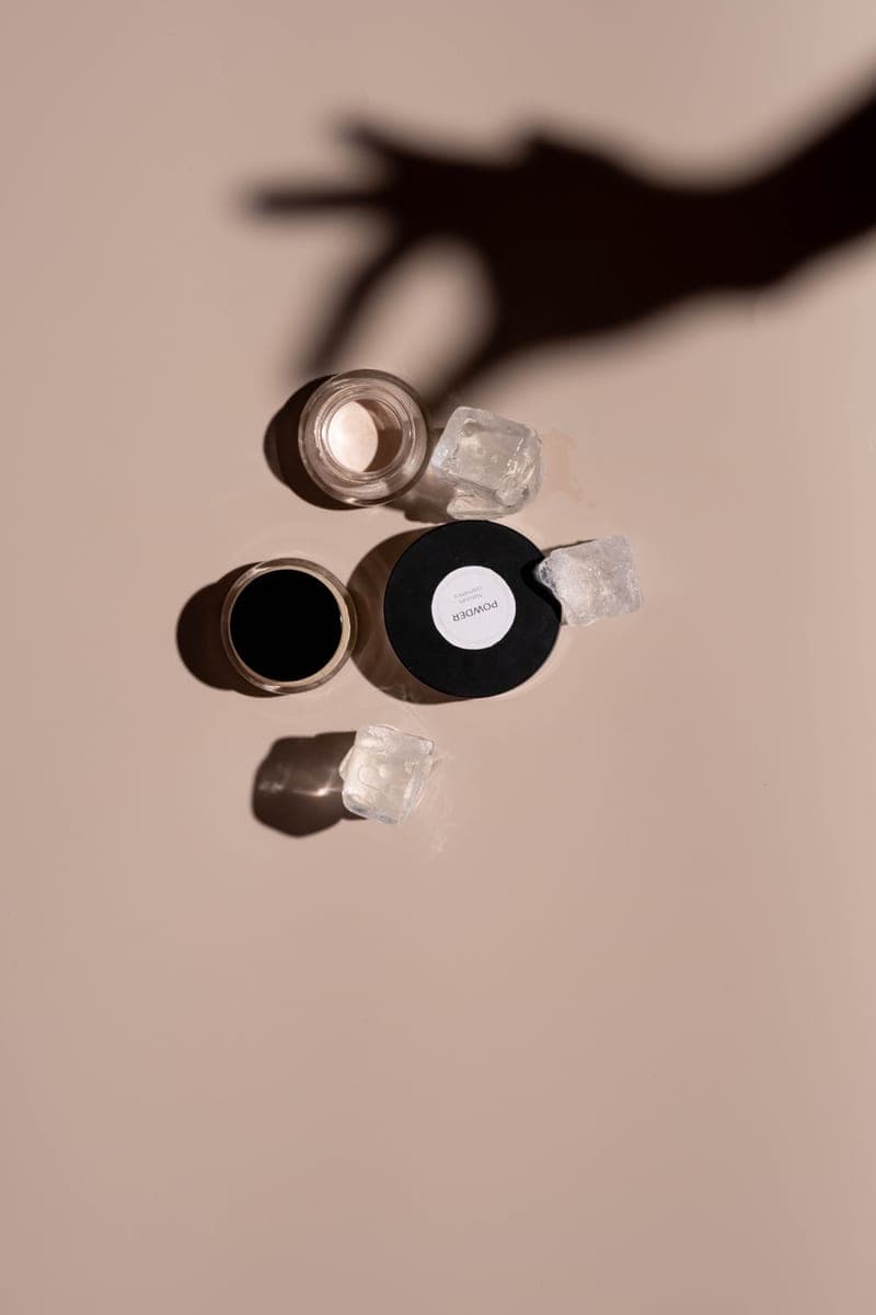 Cosmetic jars casting soft shadows on a beige background